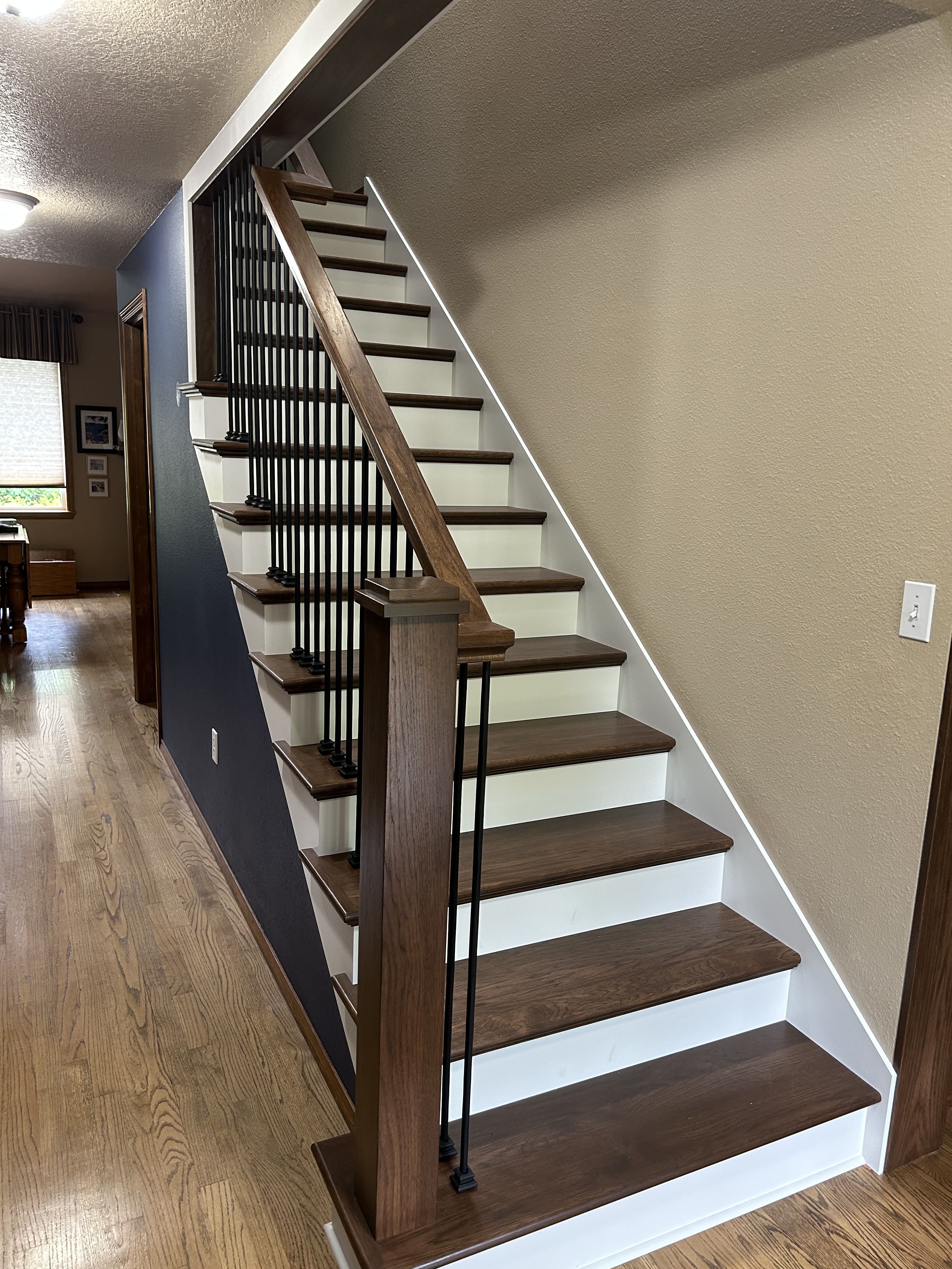 Client said to open it up so we did. After adjusting and leveling the existing staircase, we manufactured, stained, sealed and install Hickory treads, railings and posts with powder coated iron balusters. They brought us back to install new treads and risers on their lower staircase.